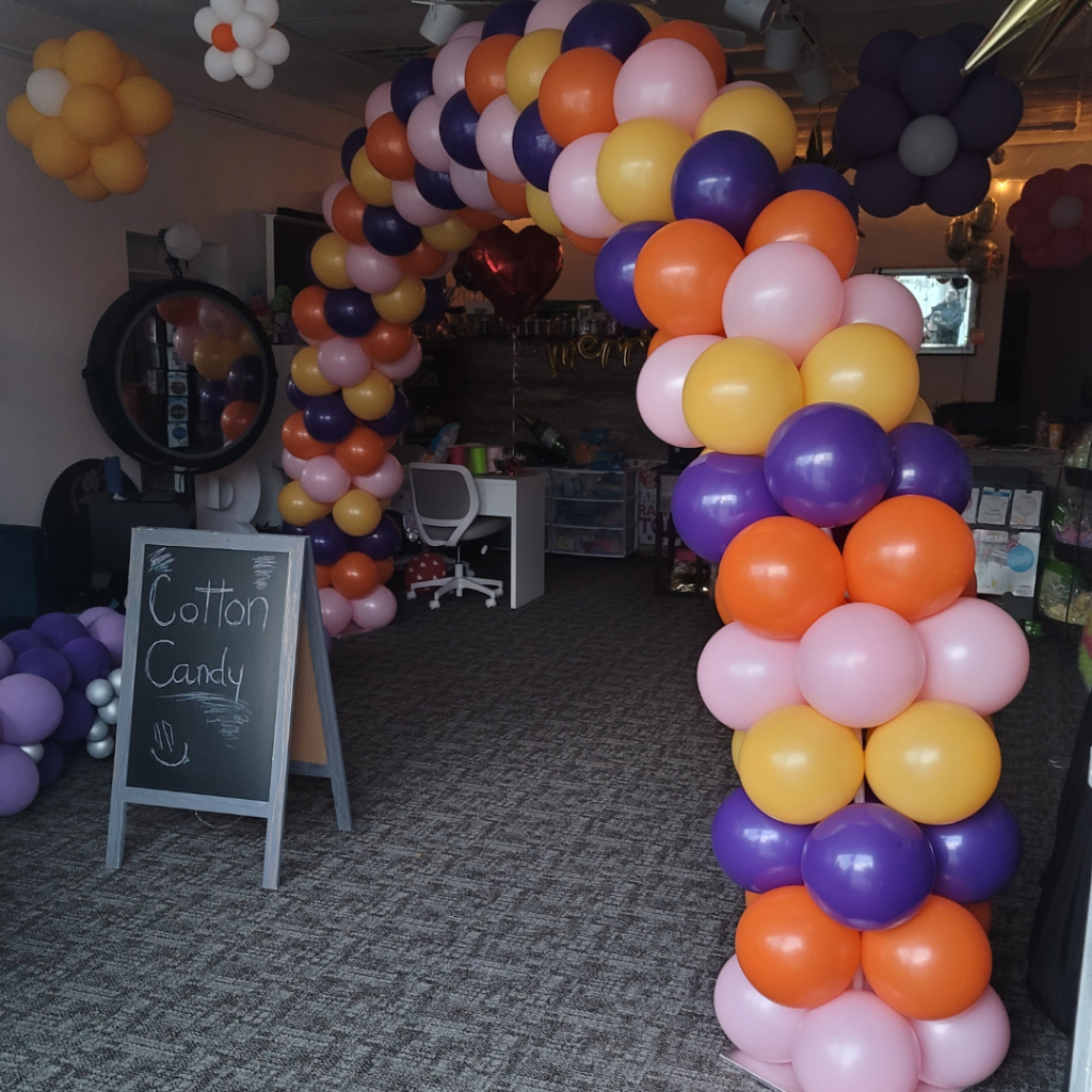 Colorful balloon arch in orange, purple, and pink, created by GBF Bespoke Balloons for Hope Lake Country Church, with 'Cotton Candy' sign in the foreground.